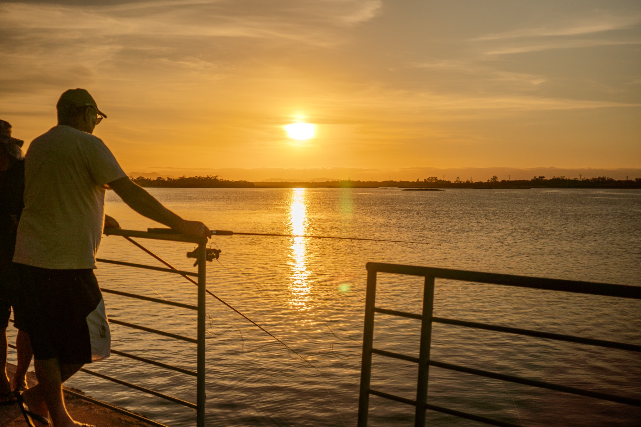Pescador contemplando o pôr do sol no píer do Complexo Turístico Antigo Porto da Balsa, em Ilha Comprida