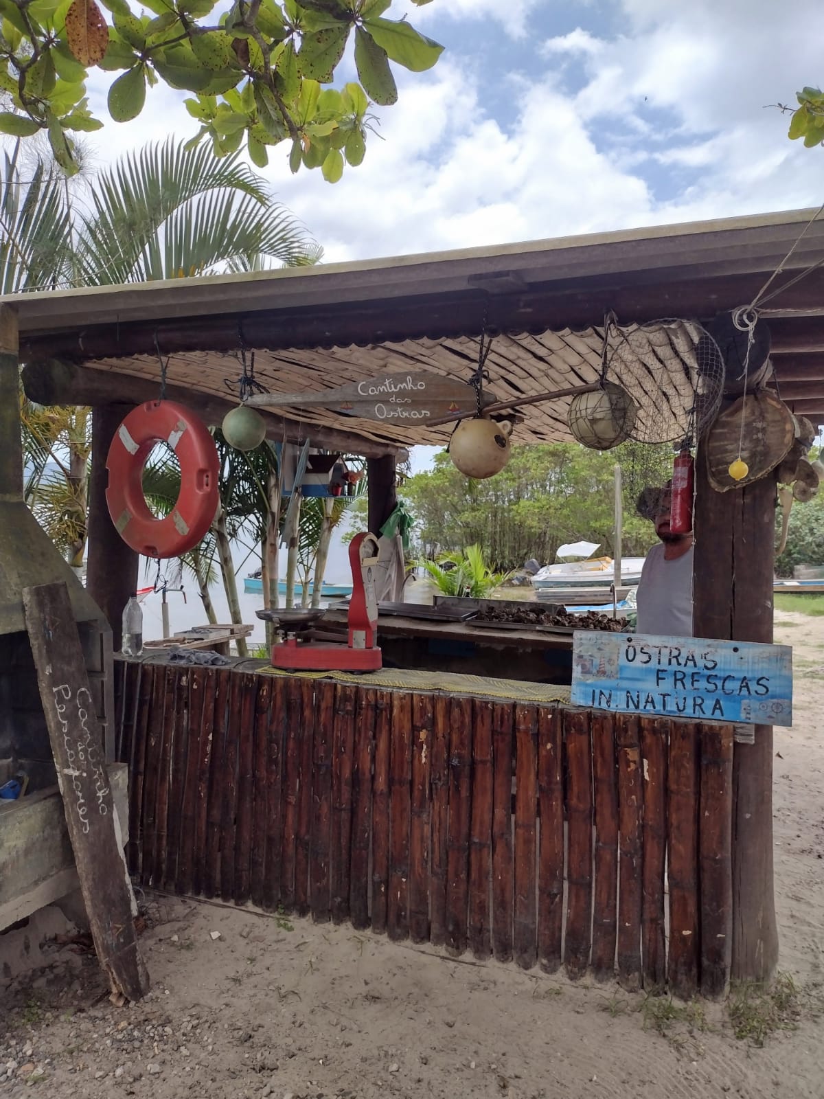 Cantinho das Ostras, ponto tradicional da gastronomia caiçara de Pedrinhas, com barcos ao fundo